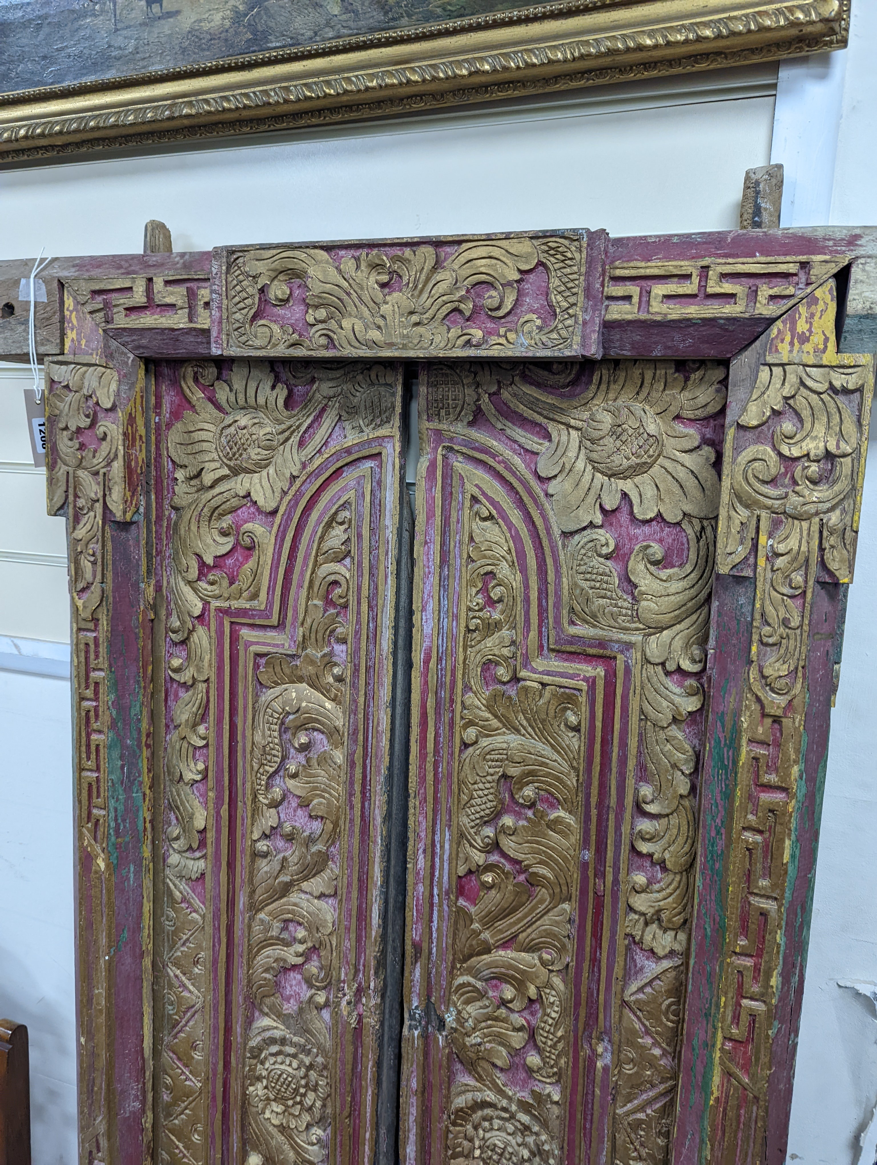 A Balinese carved giltwood door and frame, painted and gilded, width 83cm, height 174cm